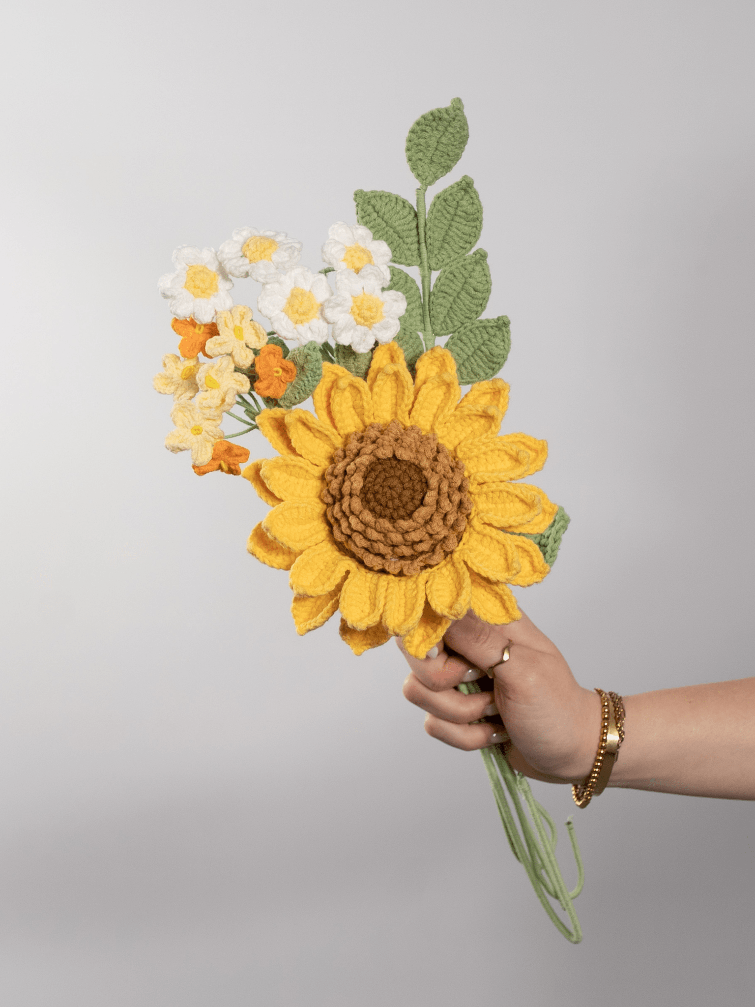 Der Blumenstrauß Golden Sun wird in der Hand gehalten. Ein Produktbild des bloomly Strauß mit grauem Hintergrund