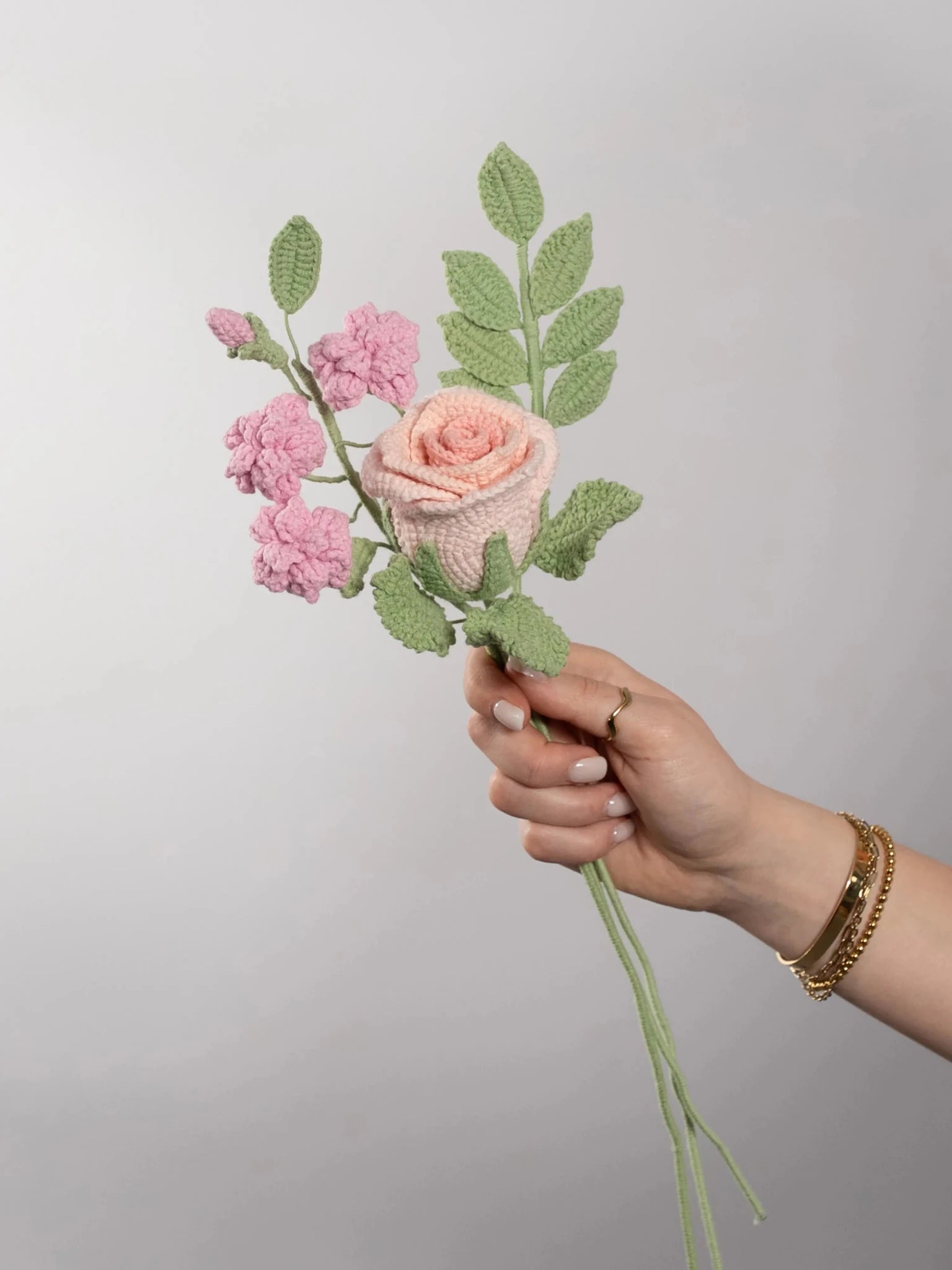 Der Blumenstrauß Little Rose wird in der Hand gehalten. Ein Produktbild des bloomly Strauß mit grauem Hintergrund