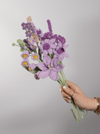 Der Blumenstrauß Purple Grace wird in der Hand gehalten. Ein Produktbild des bloomly Strauß mit grauem Hintergrund